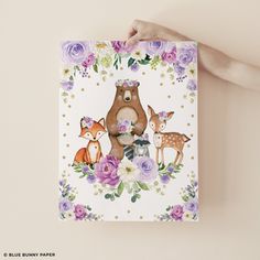 a hand holding up a card with an image of two deer and flowers on it