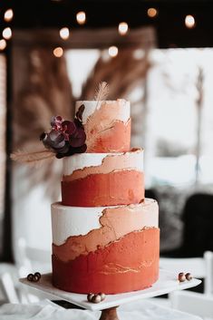 a three tiered cake with pink and white frosting on top, sitting on a table