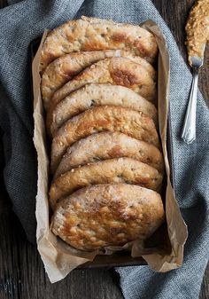 a loaf of bread sitting on top of a wooden table next to a knife and fork