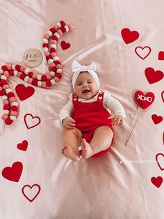 a baby is laying on a blanket with hearts around it