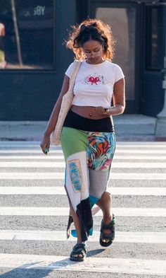 a woman walking across a street while looking at her cell phone