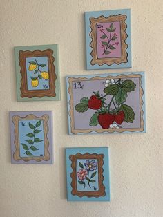 four framed pictures on the wall with flowers and fruits painted on them in different colors