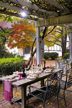 an outdoor dining table set for four under a pergolated area with lots of trees