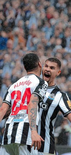 two soccer players are in the rain and one has his mouth open while the other is screaming