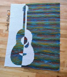 a crocheted rug with an acoustic guitar on the front and bottom, in multi - colored yarns