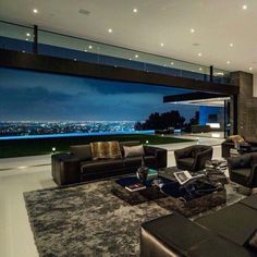 a living room filled with black furniture and a large window overlooking the city at night