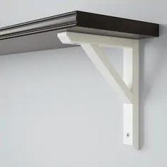 a white shelf with a black top on the wall