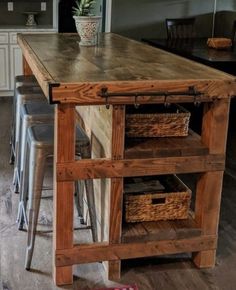 a kitchen island made out of wood with baskets on the top and two stools