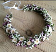 a wreath made out of flowers on top of a wooden floor next to a white ribbon