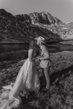 a man and woman standing next to each other in the mountains