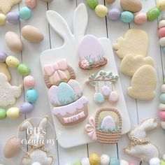 some decorated cookies are laying on a white table next to eggs and other decorations for easter