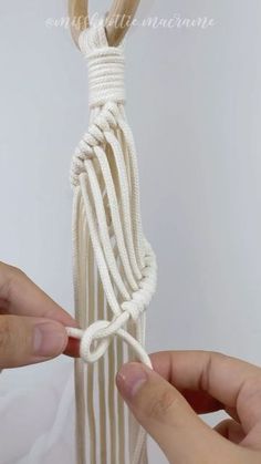 two hands are holding the ends of a white string wrapped in twine and rope