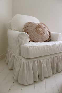 a white chair with ruffled pillows on top of it's back and bottom