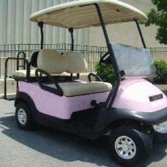 a pink and black golf cart parked in front of a building