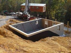 a house being built in the middle of a dirt lot with construction equipment around it