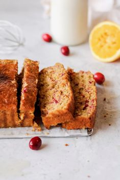 slices of cranberry orange bread sitting on a cutting board next to a glass of milk