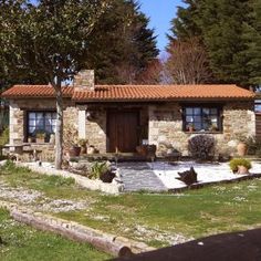 a small stone house sitting in the middle of a yard