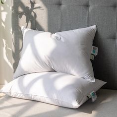 two pillows sitting on top of a bed next to a plant