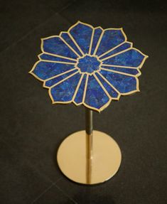 a blue flower shaped object sitting on top of a white stand with a black background