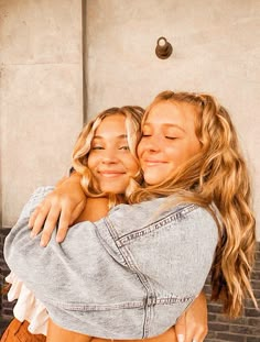 two young women hugging each other in front of a building