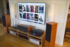 an entertainment center with speakers, subwoofers and a large television mounted on the wall