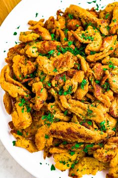 a white plate topped with fried chicken and garnished with parsley