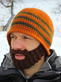 a man with a beard wearing an orange and green striped knitted hat in the snow