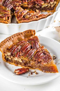 a slice of pecan pie on a plate with the rest of the pie in the background