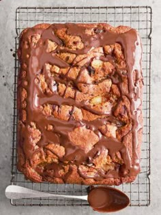 a square cake with chocolate icing on a cooling rack