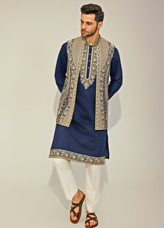 Embrace elegance with the Navy Blue Embroidery Silk Kurta Jacket Set, exquisitely crafted from a premium silk blend for a luxurious touch. The navy blue kurta features a timeless design, with classic embroidery along the collar and edges, offering a sophisticated and sleek silhouette. Paired with a beautifully beige embroidered jacket, adding a layer of refined charm. The deep navy hue contrasts strikingly with the intricate beige embroidery, creating a captivating visual appeal. Completed with crisp white pants, this set delivers a balanced and stylish look, ideal for Mehndi, Sangeet, weddings, or festive celebrations. Designed for comfort with breathable fabric, this outfit is perfect for all-day wear, merging traditional grace with contemporary elegance. Composition : Jacket, Kurta and Elegant Floral Embroidered Kurta For Winter, Traditional Straight Kurta Outerwear With Intricate Embroidery, Winter Embroidered Nehru Jacket Straight Kurta, Festive Embroidered Straight Kurta Outerwear, Elegant Straight Kurta With Chikankari Embroidery, Elegant Outerwear With Chikankari Embroidery, Embroidered Silk Bandhgala Straight Kurta, Silk Embroidered Bandhgala Kurta, Embroidered Silk Bandhgala Kurta