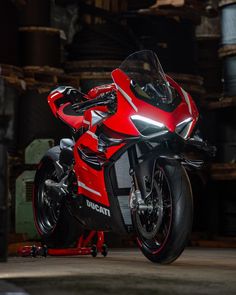 a red and black motorcycle parked on top of a metal stand in a warehouse area