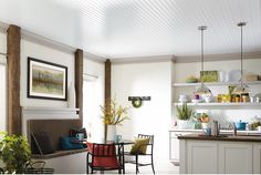 an open kitchen and dining room area with white walls, wood floors and ceiling beams