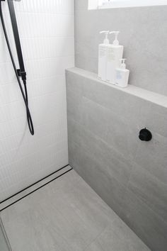 a white tiled shower stall with soap and lotion