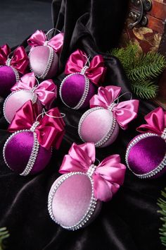 pink and purple ornaments with bows on black velvet