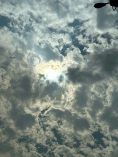 an airplane flying in the sky with clouds and sun shining through it's center