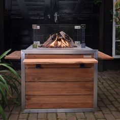 an outdoor fire pit sitting on top of a wooden table next to a potted plant