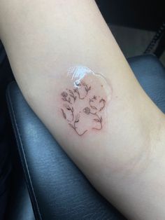 a small tattoo on the arm of a woman's left arm, with flowers in it