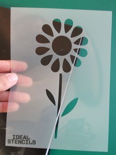 a hand holding a piece of clear paper with a flower on the front and side