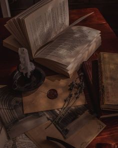 an open book sitting on top of a wooden table next to other books and papers