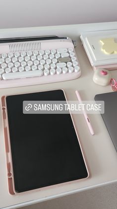 a desk with a tablet, keyboard and pen on it next to a laptop computer