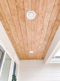 the ceiling is covered with wood planks and has a white light fixture on it