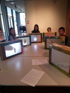 four people sitting at a table in front of laptops with pictures on the screen