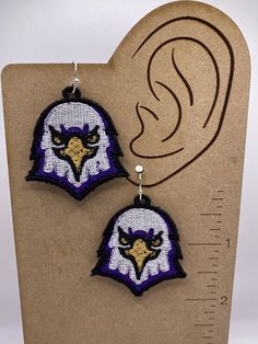 pair of earrings with an eagle on the front and back of each ear, hanging from a card board