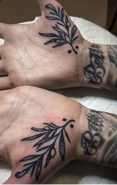 two people with tattoos on their hands and one has an olive branch tattooed on it