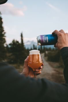 a person is holding a beer in their hand