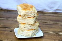 three biscuits stacked on top of each other on a white plate, sitting on a wooden table