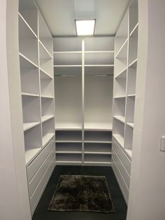 an empty walk - in closet with white shelving and carpeted flooring is shown