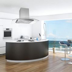 an island in the middle of a kitchen next to a large window overlooking the ocean