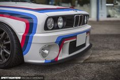 the front end of a white car with red, blue and black stripes on it