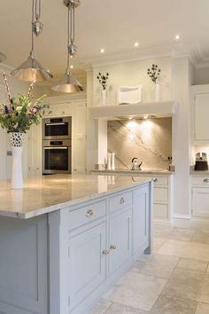 a large kitchen with an island in the middle and two lights hanging from the ceiling